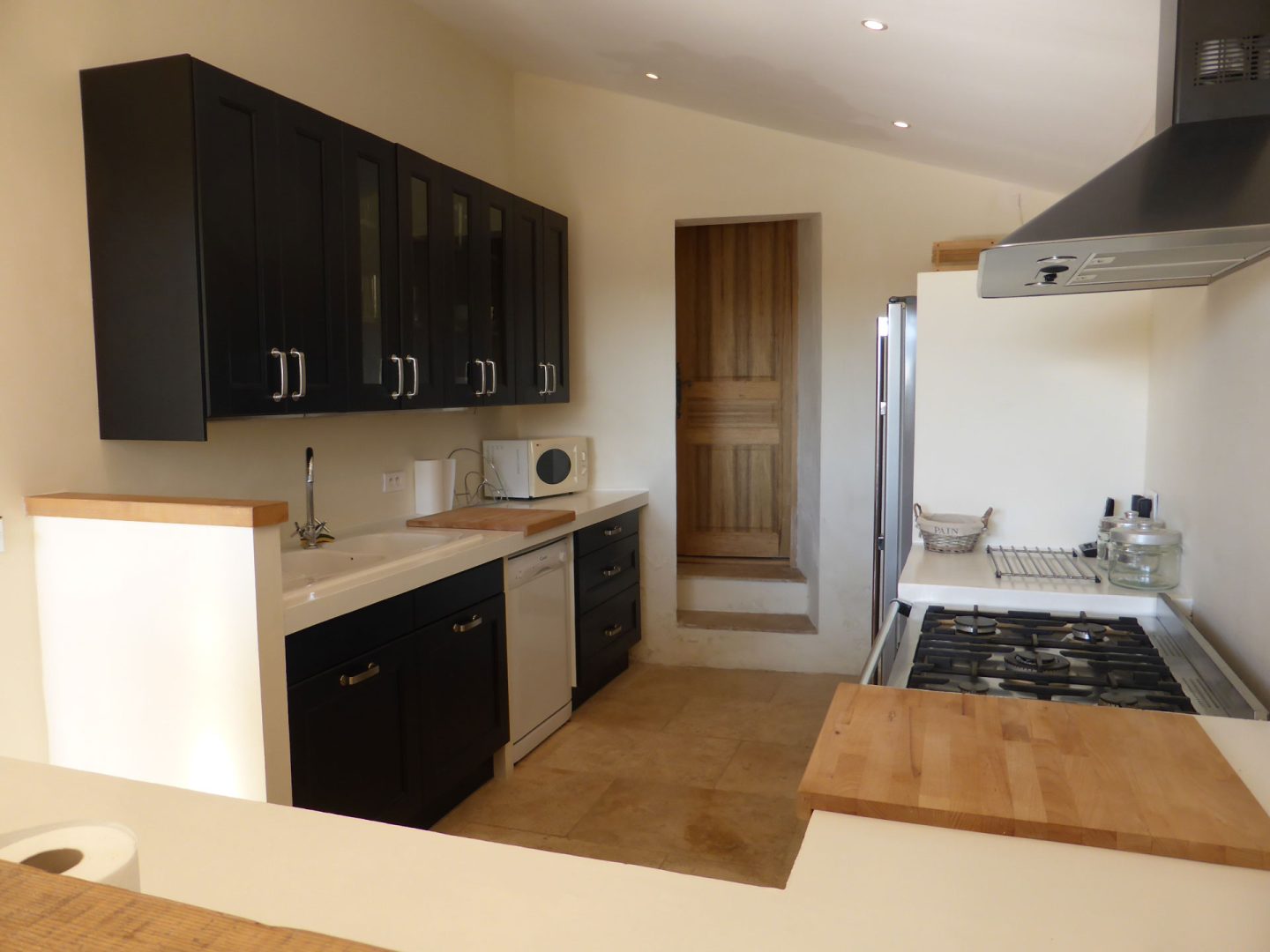 Modern black and white kitchen with rustic stone details in La Maison de Lune holiday homes Provence